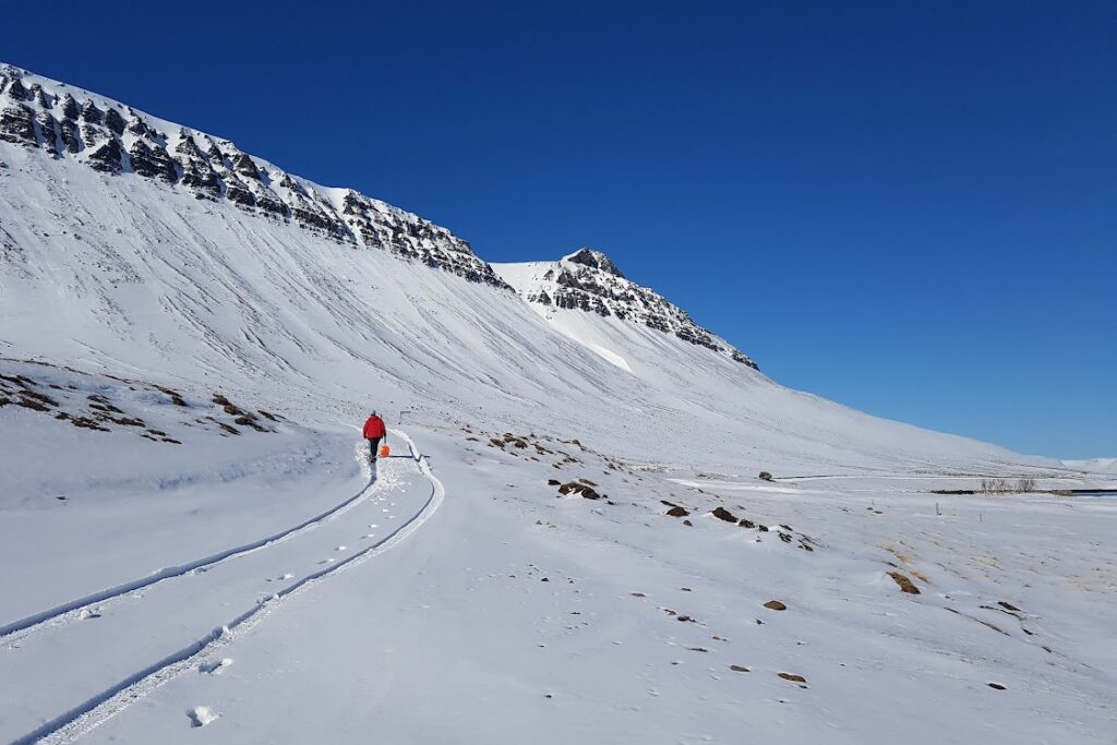 A man walking in the snow with a shovel