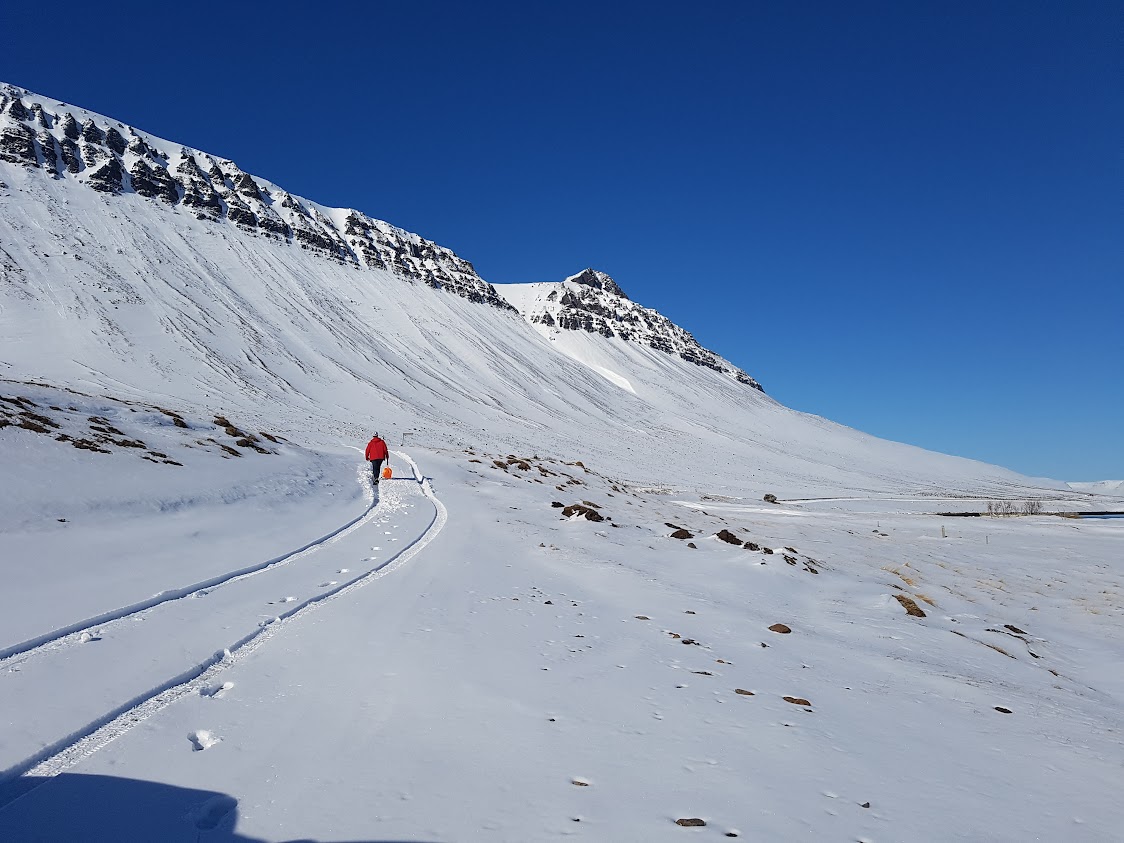 A man walking in the snow with a shovel