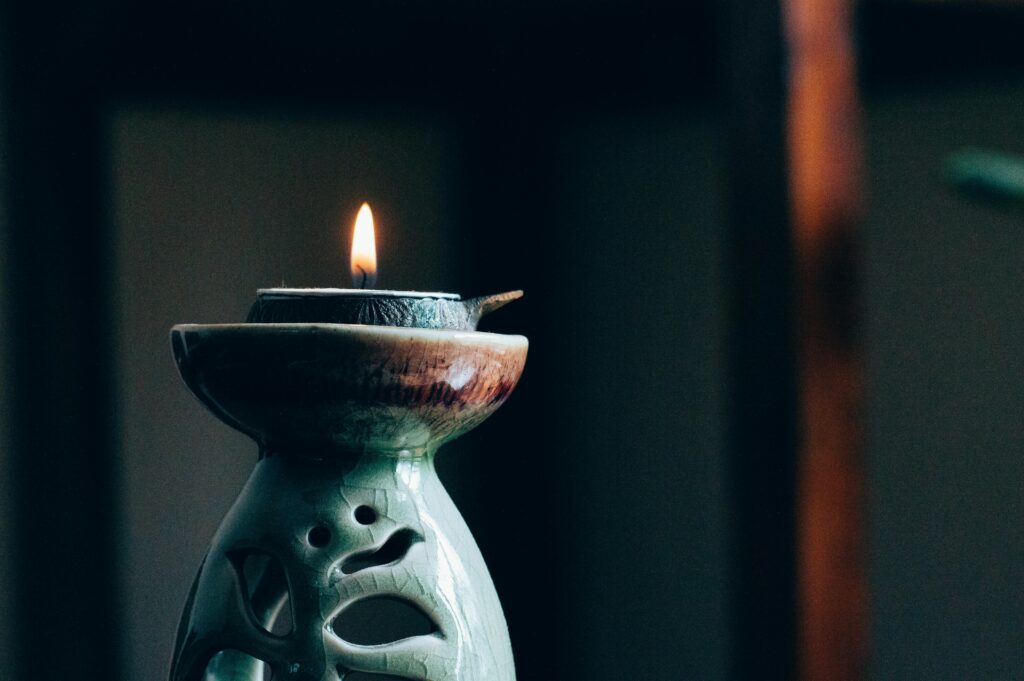 A candle lighting on a green candle oil burner