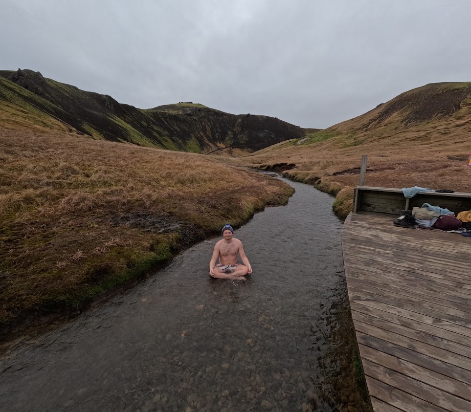 Andri sitting in Reykjadalur hot spring thermal river