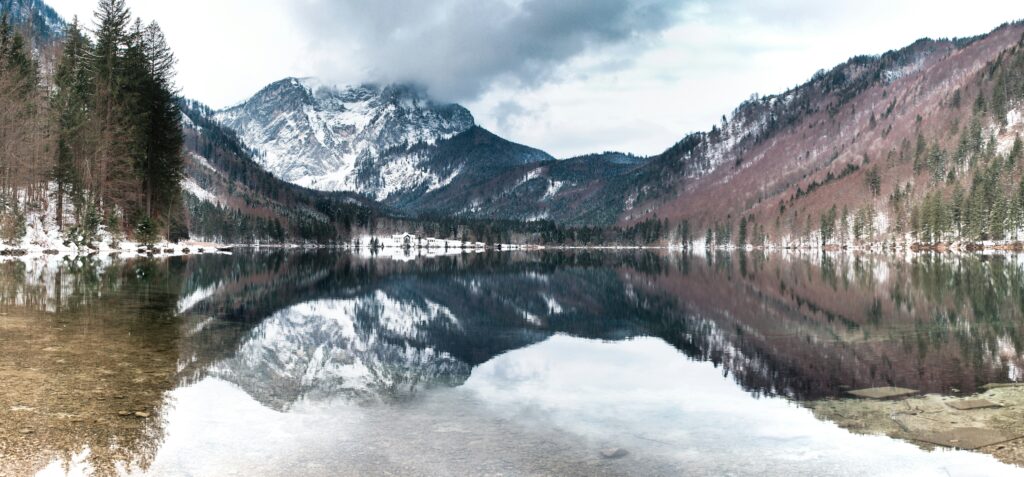 A snowy mountain range surrounding cold water