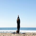 a person doing a standing yoga pose on the beach