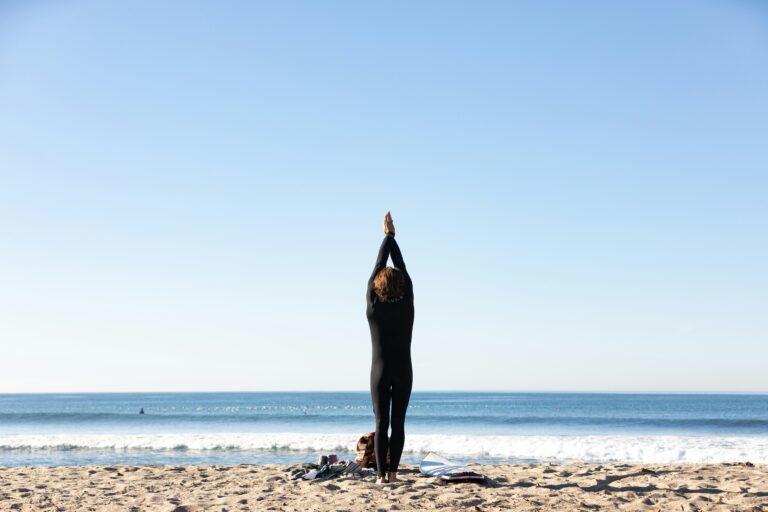 a person standing on the beach with their hands up to the sky practicing quick breathwork