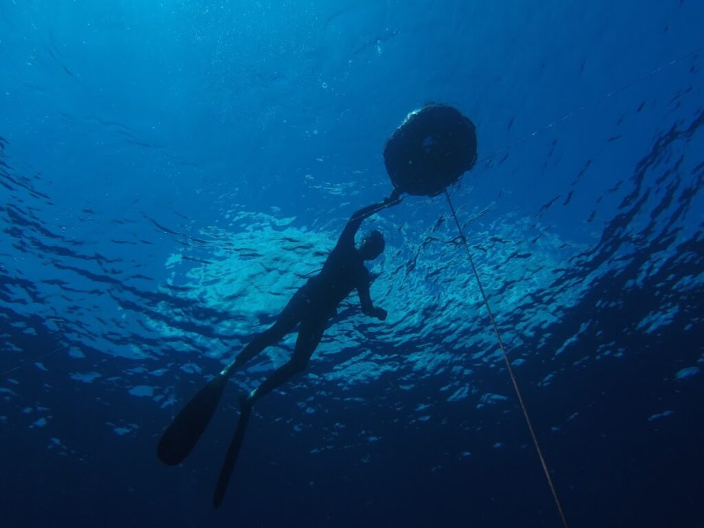 Freediving at depth looking up at another freediver