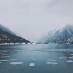 A winter frozen lake with snowy mountains