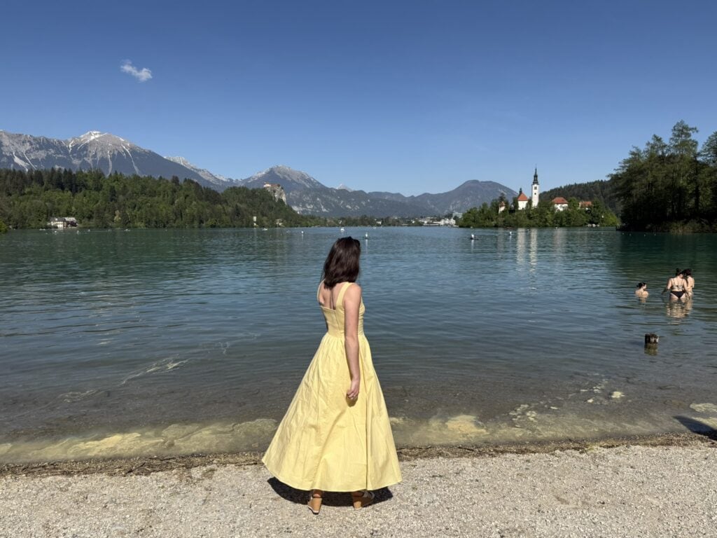 Elaina standing in a yellow dress looking at the lake practicing breathwork for stressed moms